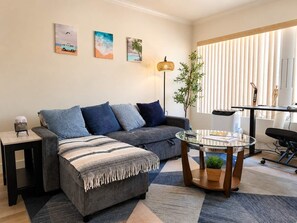 Ein modernes Wohnzimmer mit Sofa, Hocker, Couchtisch und einem Kunstwerk an der Wand.