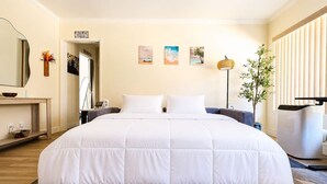 Camera d'albergo con un letto grande, comodini, uno specchio, opere d'arte al muro e una pianta.