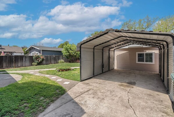 Un garage fermé avec une allée en béton, une clôture en bois et une pelouse.