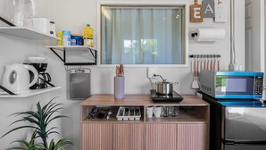 A compact kitchen with a window, shelves with kitchenware, a microwave, and a small refrigerator. - East SJ Entire 4Br Home Quiet (San Jose)