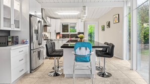 A modern kitchen with white cabinetry, a stainless steel refrigerator, and a central island with bar stools. - Entire 3br House With Playground (Palo Alto)