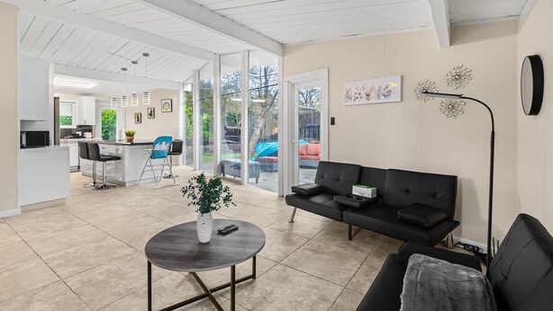 A spacious living area with a black sofa, a coffee table, and a dining area with chairs. - Entire 3br House With Playground (Palo Alto)