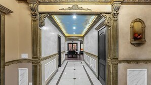 Un pasillo con detalles ornamentales dorados, suelo de mármol y techo con tragaluces.