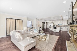 A spacious living area with a sofa, a coffee table, and a kitchen in the background. - SJ Downtown 5 BR Stunning House (San Jose)