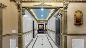 A hallway with ornate moldings, a marble floor, and a ceiling with a skylight.