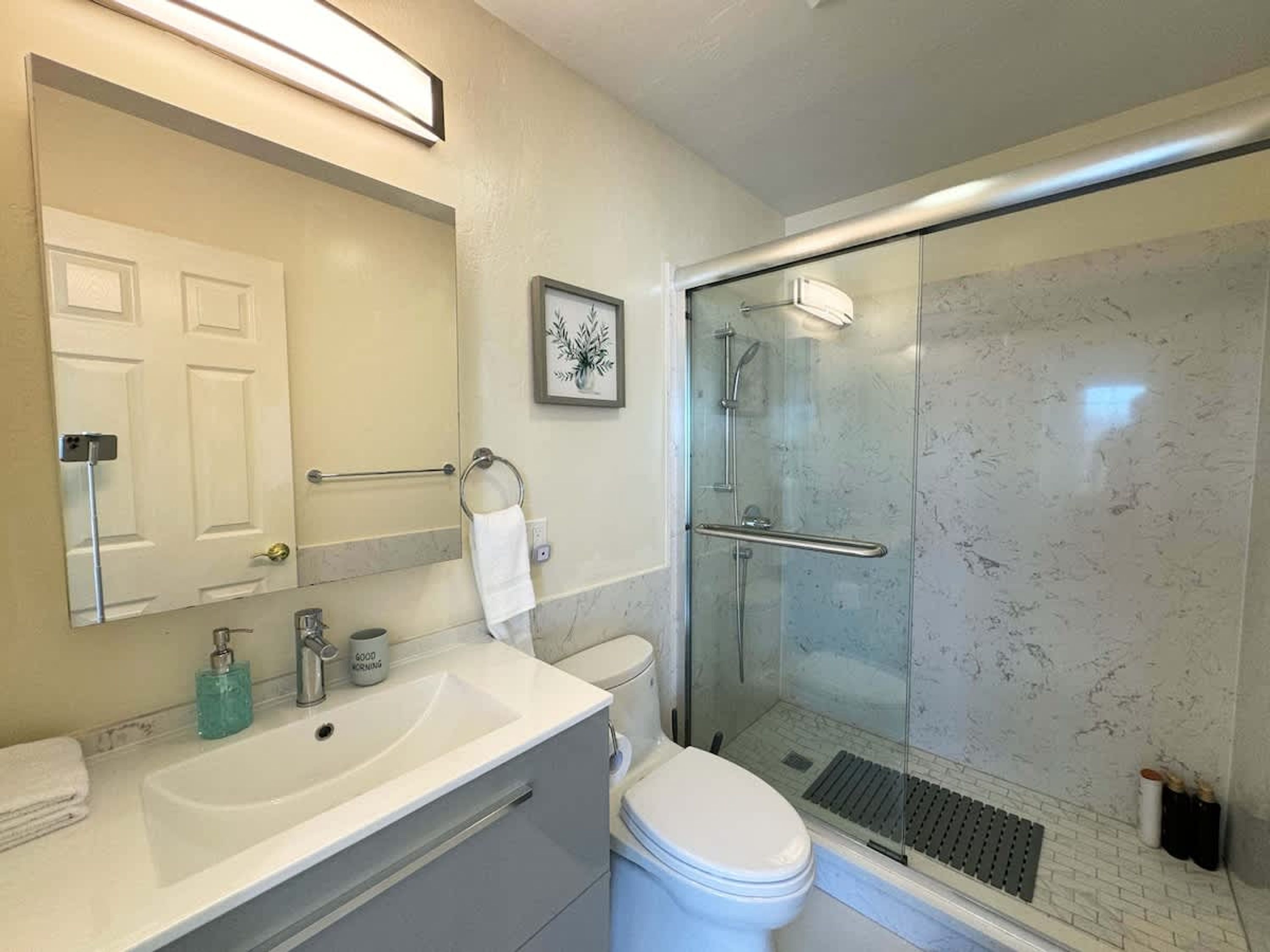 A bathroom with a white sink, toilet, and glass-enclosed shower.