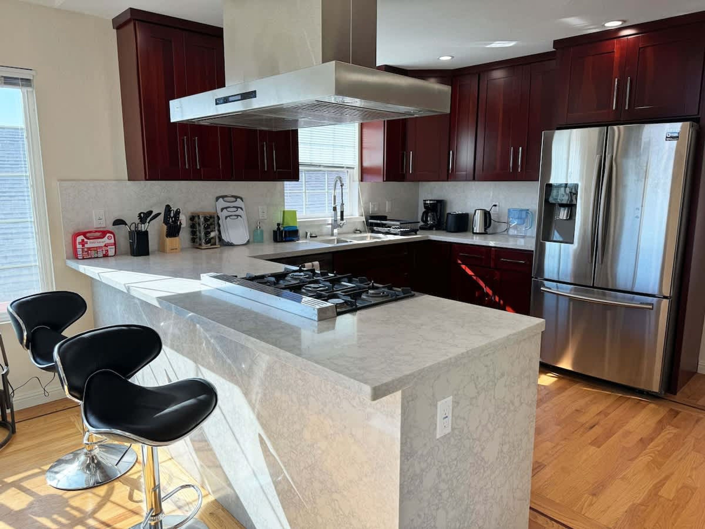 A modern kitchen with dark wood cabinets, stainless steel appliances, and a central island with bar stools.