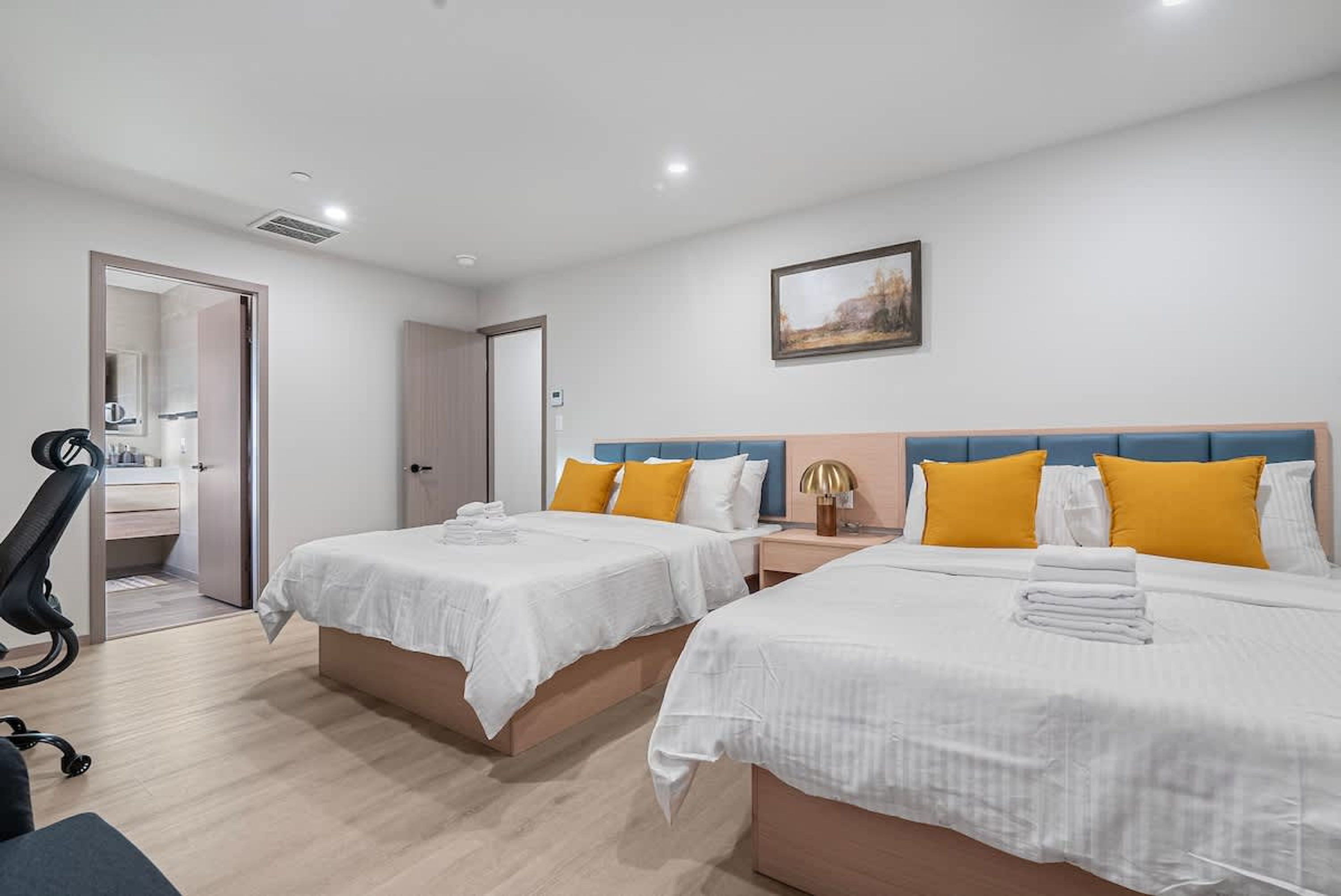 Une chambre d’hôtel avec deux lits, un bureau et une chaise.