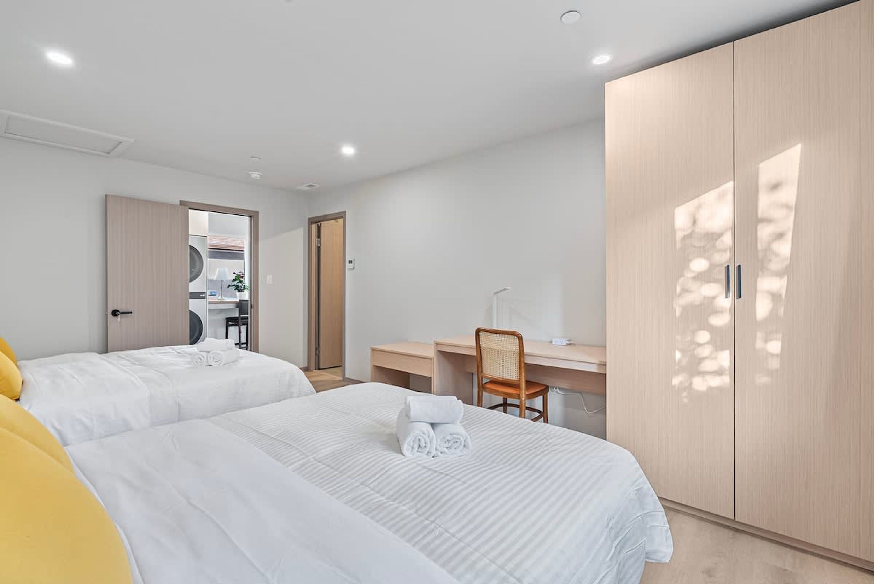 A hotel room with two beds, a desk, and a wardrobe.