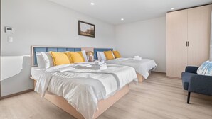 Quarto de hotel moderno com duas camas, um sofá e um guarda-roupa.