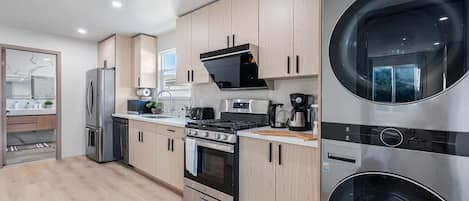 A modern kitchen with stainless steel appliances, wooden cabinets, and a built-in washer and dryer.