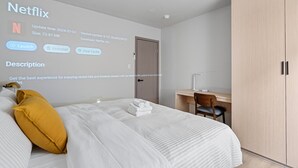 Moderni hotellihuone, jossa on siististi pedattu sänky, työpöytä tuolilla ja vaatekaappi.