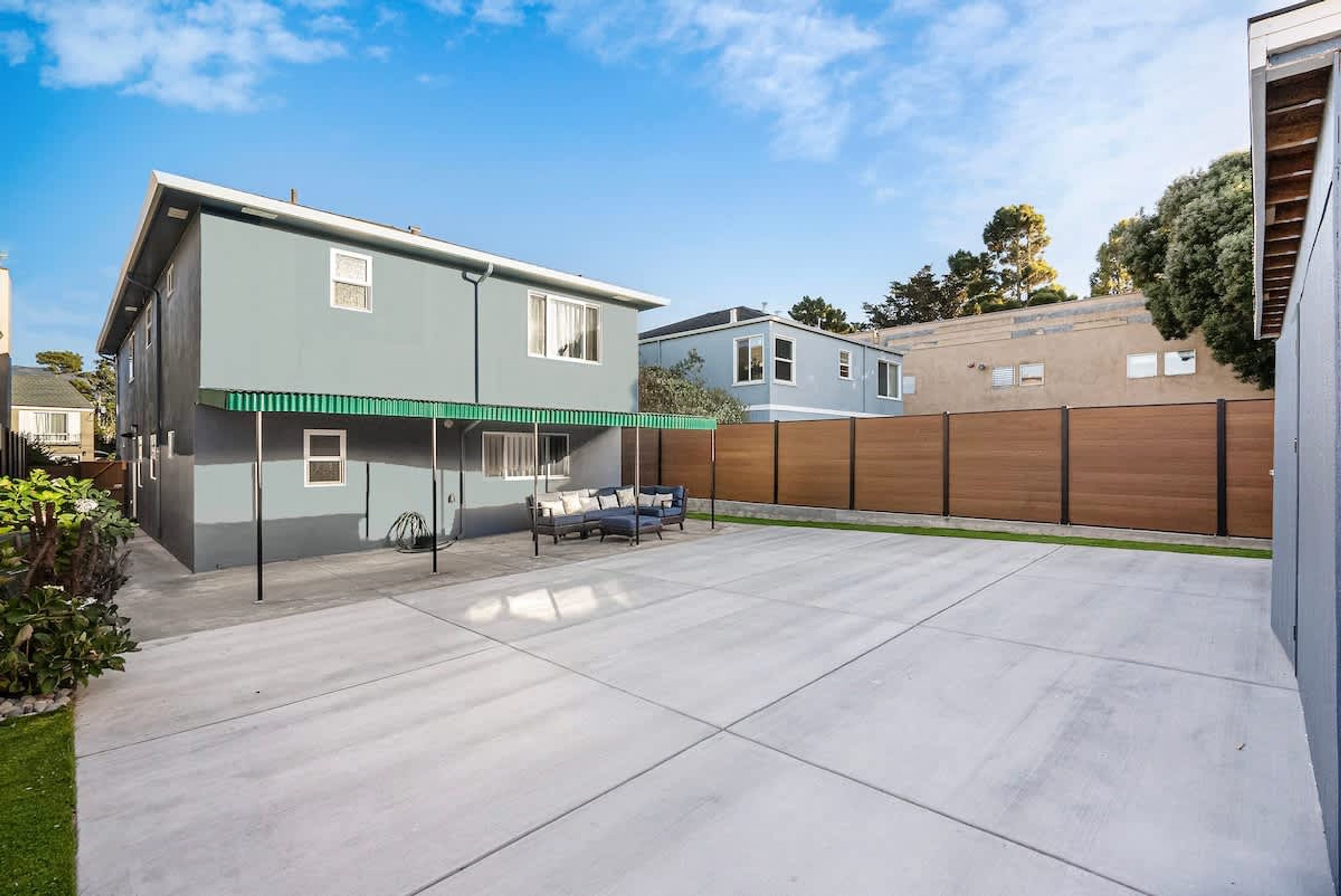 Une maison moderne à deux étages dotée d’un patio couvert.