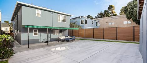 Une maison moderne à deux étages dotée d’un patio couvert.