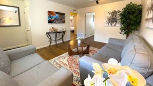 A modern living room with a grey sofa, a round coffee table, and a TV mounted on the wall. - Campbell Cozy Bright 2B 1b AC Close to Downtown (Campbell)