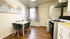 A compact kitchen with a dining area, featuring a white stove, cabinets, and a dining table with chairs. - Campbell Cozy Bright 2B 1b AC Close to Downtown (Campbell)