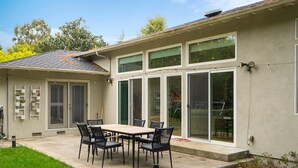 A patio with a table and chairs, a covered area with a roof, and a sliding glass door leading to a garage.