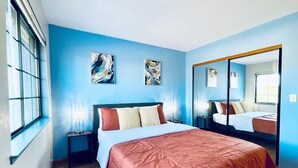 A bedroom with a large bed, a nightstand, a mirror, and abstract art on the wall. - Vallejo Beautiful 4br Home wt Mountain View Napa (Vallejo)