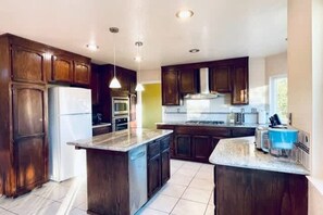 A kitchen with dark wooden cabinets, a central island, and a built-in oven. - Vallejo Beautiful 4br Home wt Mountain View Napa (Vallejo)