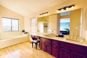 A modern bathroom with a large bathtub, two sinks, and a vanity with cabinets. - Vallejo Beautiful 4br Home wt Mountain View Napa (Vallejo)