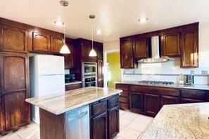 A kitchen with wooden cabinets, a granite countertop, stainless steel appliances, and pendant lighting. - Vallejo Beautiful 4br Home wt Mountain View Napa (Vallejo)