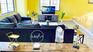 A living room with a black sofa, a wooden coffee table, and a television on a stand. - Vallejo Beautiful 4br Home wt Mountain View Napa (Vallejo)