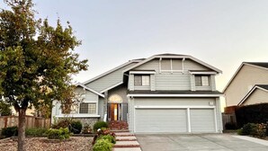 A two-story residential house with a garage, a front porch, and a landscaped front yard. - Vallejo Beautiful 4br Home wt Mountain View Napa (Vallejo)