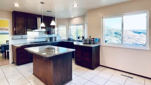 A modern kitchen with dark wood cabinets, a large island, and pendant lighting. - Vallejo Beautiful 4br Home wt Mountain View Napa (Vallejo)