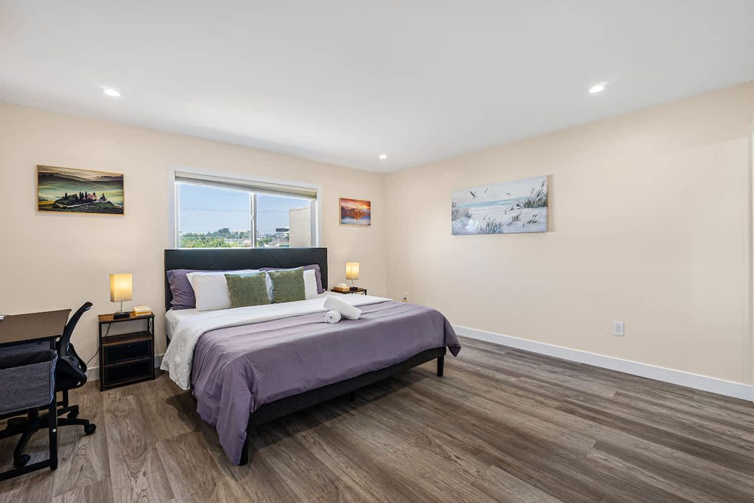 A bedroom with a bed, a desk, and two bedside lamps.