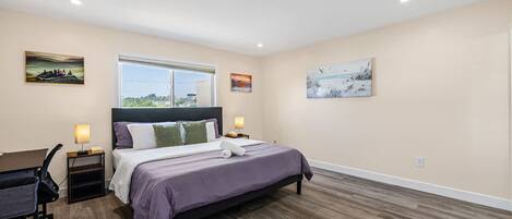 A bedroom with a bed, a desk, and two bedside lamps.