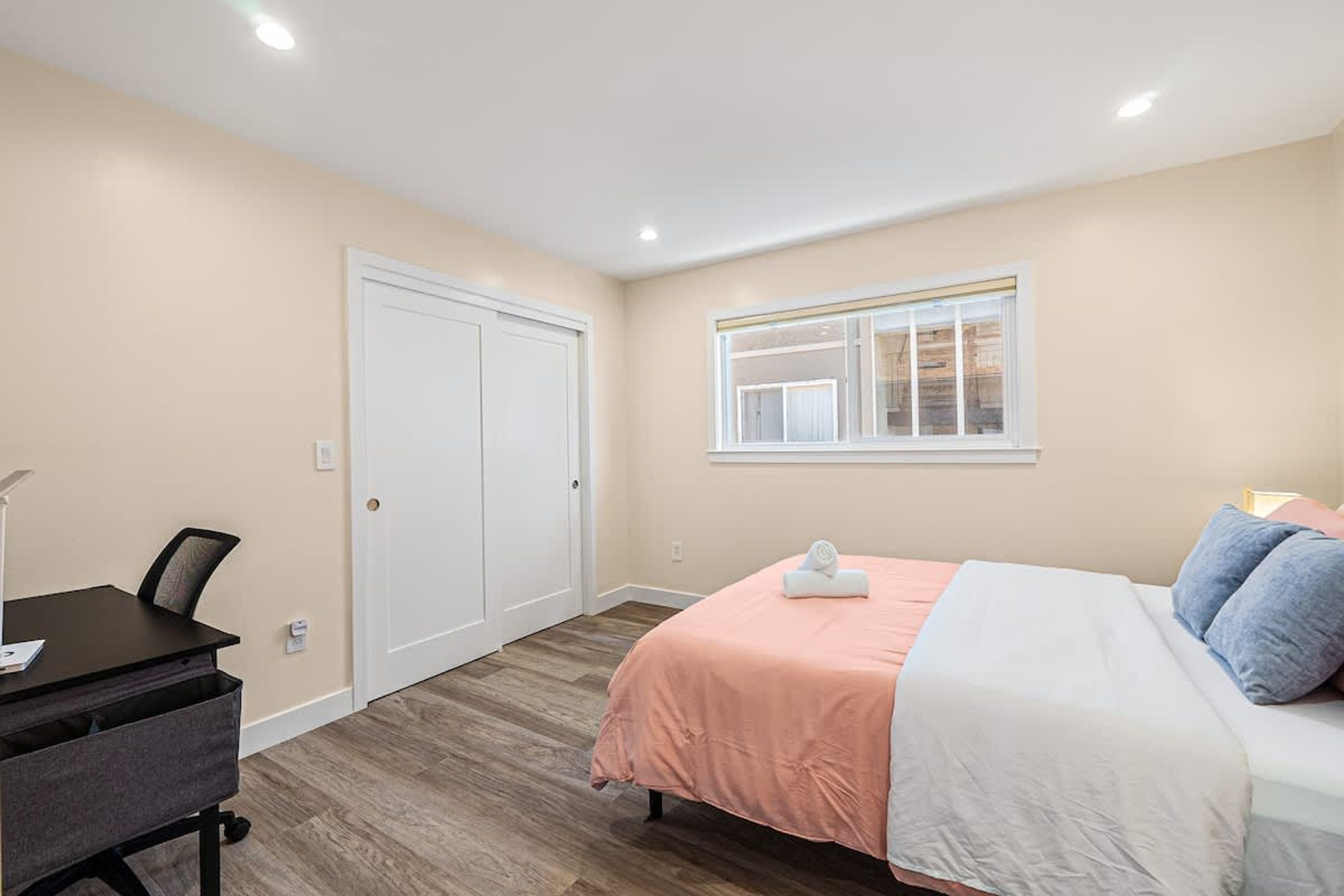 A bedroom with a bed, a desk, and a wardrobe.