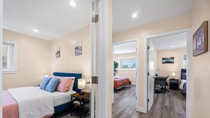 Ein Schlafzimmer mit Bett, Nachttisch, Lampe und Schreibtisch mit Stuhl.