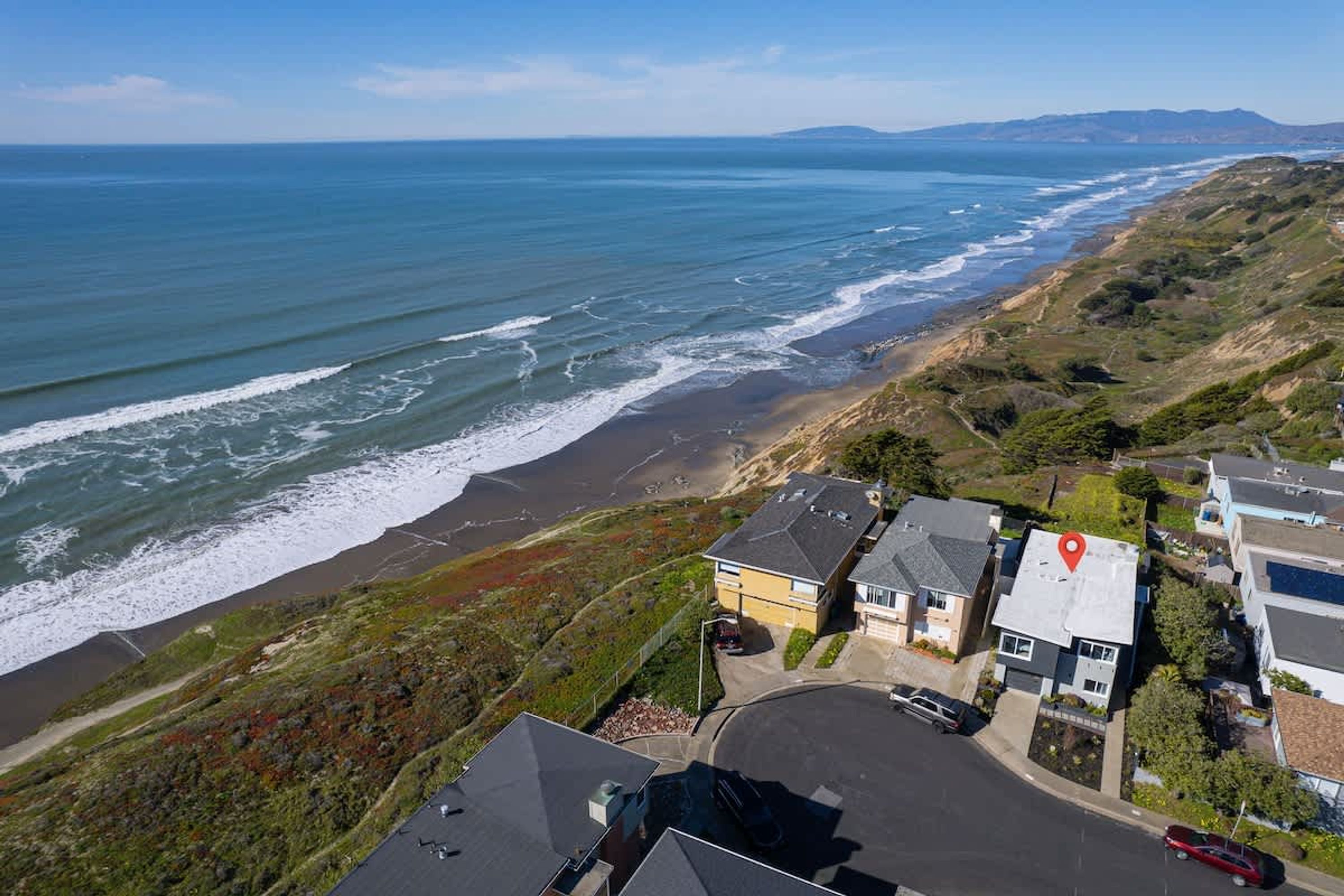 A coastal residential area with houses, a beach, and ocean views.