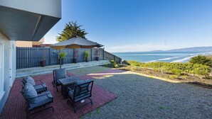 Un patio con mobiliario exterior, una pérgola y vistas al océano.