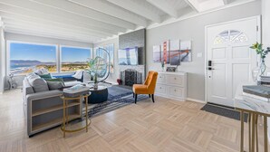 Un salón espacioso con un amplio ventanal, chimenea y vistas al puente Golden Gate.