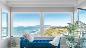 Una habitación con un ventanal grande, un sofá azul, un sillón colgante y una alfombra con forma de estrella de mar.