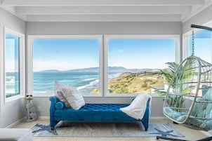 Una habitación con un ventanal grande, un sofá azul, un sillón colgante y una alfombra con forma de estrella de mar.
