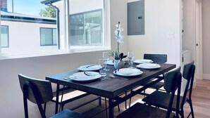 A dining area with a rectangular table set for four, positioned near a large window with blinds. - New 3b3b Home Gogle Speed Wifi (Sunnyvale)