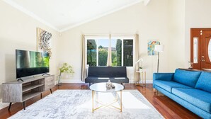 Un salon avec un téléviseur, un canapé et un divan bleu.