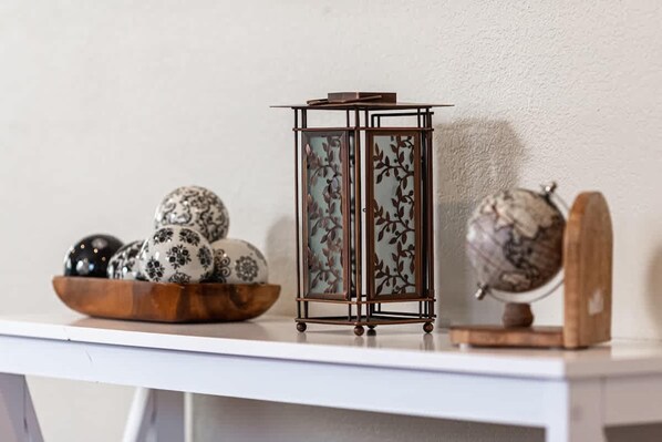 A white shelf with decorative items including a wooden bowl with patterned eggs, a metal lantern with floral designs, and a globe on a wooden stand. - Beautiful 4Br House Near Napa (Vallejo)