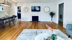 Un salon moderne avec une cheminée, un coin repas et une cuisine en arrière-plan.