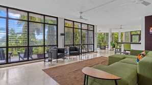 A spacious living area with large windows, a green sofa, and a small table.