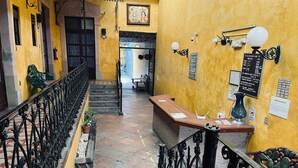 A hallway with a staircase, a reception desk, and a wall-mounted sign. - Meson Acueducto (Querétaro)