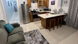 A compact kitchen with a central island, wooden cabinets, and a refrigerator. - Cozy air conditioned 2-bedroom apartment in charming Charles Town community. (Charles town)