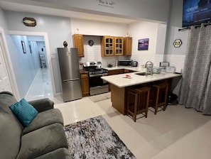 A compact kitchen with a central island, wooden cabinets, and a refrigerator.