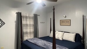 A bedroom with a four-poster bed, a ceiling fan, a wall-mounted light, and a motivational quote. - Cozy air conditioned 2-bedroom apartment in charming Charles Town community. (Charles town)