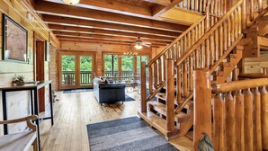 A spacious wooden interior with a staircase, a dining area, and a view of the outdoors. - Mountain Views, 🎯Game Room, Sleeps 20, Near Dollywood & Gatlinburg (Sevierville)