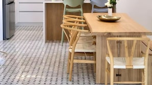 Una cocina moderna con armarios de madera, salpicadero de mármol y comedor con mesa y sillas de madera.