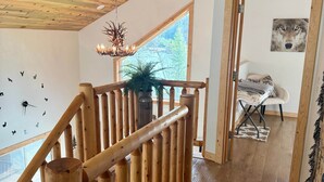Una escalera de madera con vistas a una habitación que muestra un cartel que dice 'Hibernation Station' y una ventana con vista a árboles.