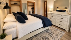 A bedroom with a bed, bedside lamps, a dresser, a mirror, and a closet.